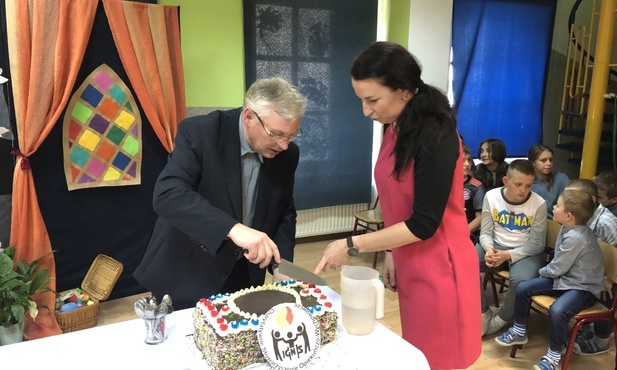 Urodzinowy tort zdobiło logo "Ignis", a kroili: ks. Ignacy Czader i Agnieszka Habrzyk, obecna szefowa świetlicy
