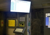 Biletomaty ustawione zostały w holu głównym szpitala. Nad nimi znajdują się ekrany, które wyświetlają numery pacjentów.