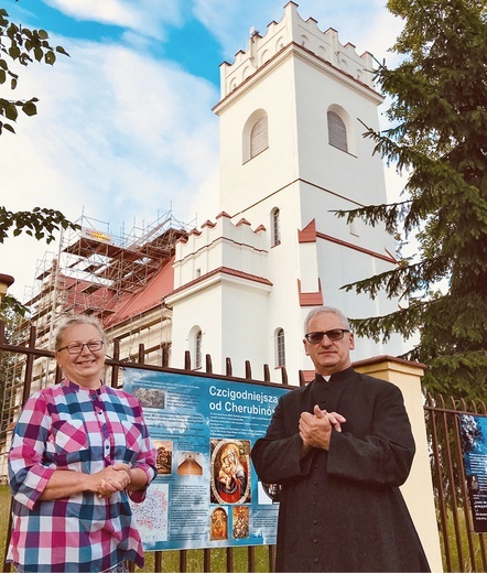 Prof. Bogumiła Jędrzejewska i proboszcz, ks. Bogdan Popławski przed kościołem parafialnym pw. św. Teresy od Dzieciątka Jezus w Białowieży.