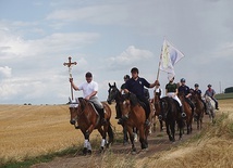 ▲	Na czele pielgrzymki jadą jeźdźcy z krzyżem i chorągwią stowarzyszenia. 