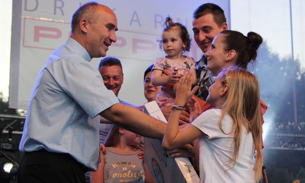Ks. proboszcz Wiesław Ostrowski wręcza nagrody rodzinie, która zwyciężyła w familijnym torze przeszkód.