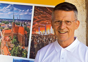Brat Marek w Taizé przy tablicy promującej Europejskie Spotkanie Młodych we Wrocławiu