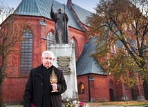 Ks. Henryk Romanik z relikwiarzem przed pomnikiem Ojca Świętego, który upamiętnia papieską wizytę z 1991 roku.