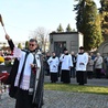 Ks. Jerzy Jurkiewicz kropi wodą święconą groby podczas procesji we Wszystkich Świętych.