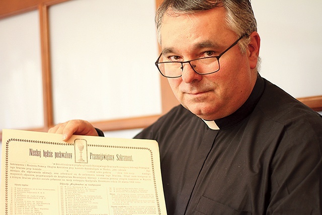 	Ksiądz proboszcz Jacek Gołębiowski z historycznym dokumentem bractwa eucharystycznego. 