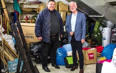 Prezydent Dariusz Bożek oraz ks. Kwiczala, a za ich plecami część zgromadzonych darów.