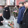 Jan Kondek zapala znicz przed odrestaurowaną płytą pamiątkową.