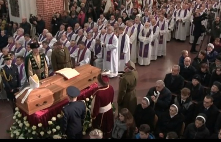 Trumna otoczona kapłanami i wiernymi modlącymi się w czasie Mszy św. pogrzebowej.