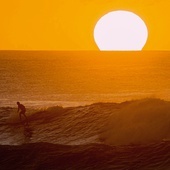 Mężczyzna surfujący na Hawajach o zachodzie słońca. 
28.01.2020 Plaża na wyspie Oahu, Stany Zjednoczone