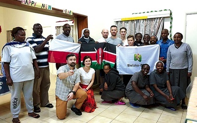 Wolontariusze z flagami polską i kenijską wśród misjonarzy w Kenii.