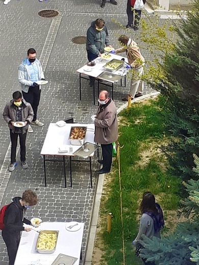 Ks. Andrzej Kiciński nie tylko dowozi studentom jedzenie, ale także sam je rozdaje.