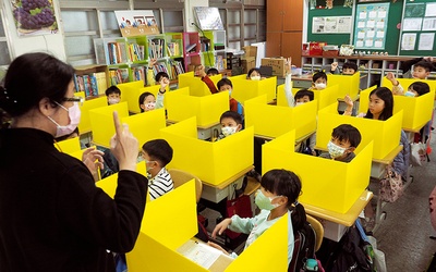 Uczniowie oddzieleni od siebie ściankami z plastiku uczestniczą w zajęciach w szkole podstawowej Dajia w Tajpej. 3.03.2020 Tajwan