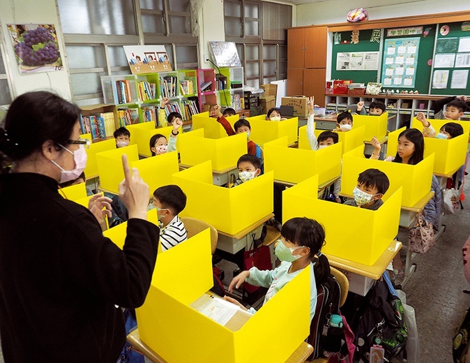 Uczniowie oddzieleni od siebie ściankami z plastiku uczestniczą w zajęciach w szkole podstawowej Dajia w Tajpej. 3.03.2020 Tajwan