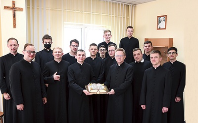 ▲	Alumni mogli skosztować tortu, który miał kształt księgi Pisma Świętego. Z ciastem z prawej ks. Jacek Kucharski.