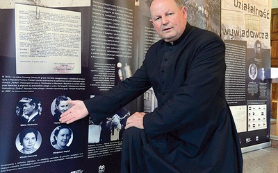 ▲	Ksiądz Krzysztof Chodowicz pokazuje fotografię swego ojca, umieszczoną na jednej z tablic wystawy IPN.