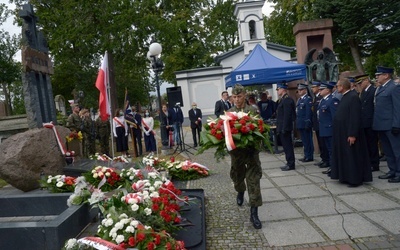 Kwiaty przy pomniku katyńskim składają przedstawiciele służb mundurowych.