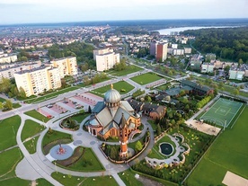 ▲	Świątynia jest bardzo malowniczo położona. W tle Jezioro Paprocańskie.