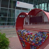 Mieszkańcy wypełniają wielkie serce plastikowymi korkami.