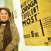 ▲	Kraków, 2005 rok. Artystka w swoim mieszkaniu, przy plakacie wieczoru literackiego studentów polonistyki z 1938 r., gdzie recytowała wiersze wraz z Karolem Wojtyłą.