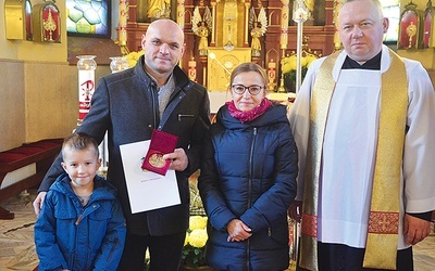 	Michał Gocal z żoną, synem i ks. Markiem Kitą.