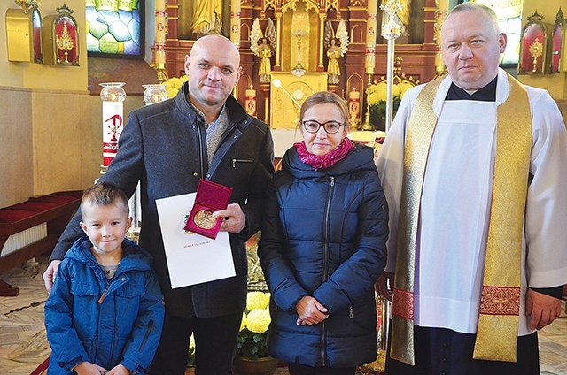 	Michał Gocal z żoną, synem i ks. Markiem Kitą.