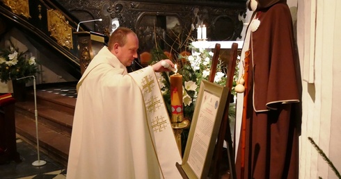 Ks. kan. Krystian Kletkiewicz, proboszcz archikatedry oliwskiej, zapala jubileuszową świecę.