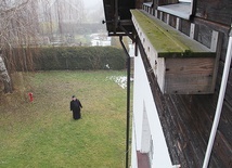 Budki na murze plebanii i ksiądz proboszcz.