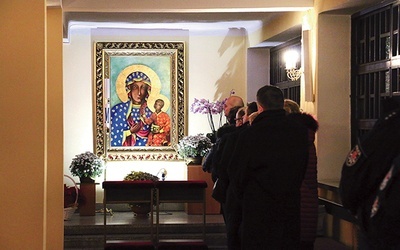 W bocznej nawie wierni modlą się przy dużej ikonie Matki Bożej Częstochowskiej. 
