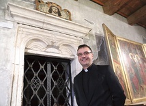 	Ks. dr Piotr Pasek przy jednym z kamiennych portali w Domu Mikołajowskim.