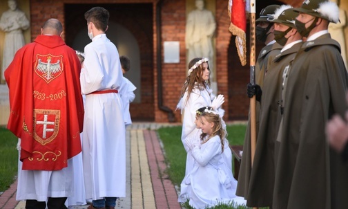 Ks. Sroka rozdaje Komunię św. dzieciom pierwszokomunijnym.