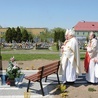 Modlitwa przy krzyżu na cmentarzu parafialnym. W tle budynki schroniska.