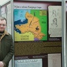 Bartosz Staręgowski zachęca do zapoznania się z pismami, zdjęciami i mapami prezentowanymi na ekspozycji.