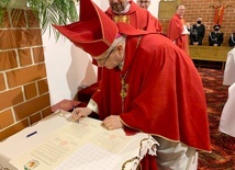 Biskup podpisujący stosowne dokumenty związane z poświęceniem nowej kaplicy.