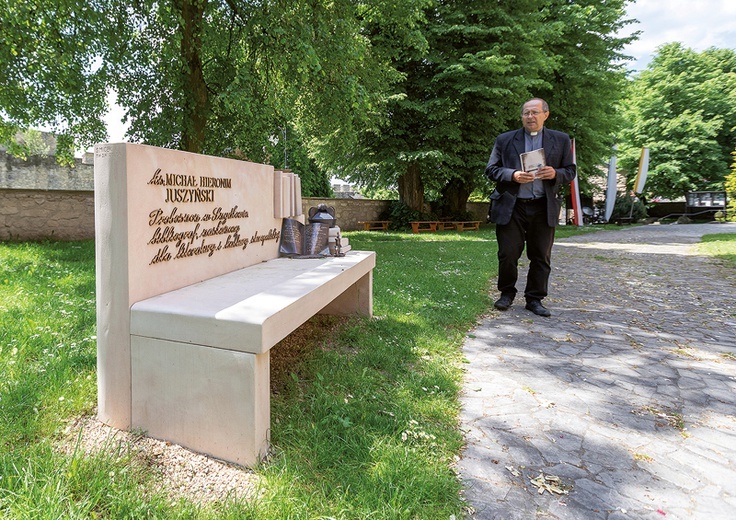 Proboszcz ks. Ryszard Piwowarczyk obok ławeczki ku czci zasłużonego dla miasta ks. Michała Juszyńskiego.