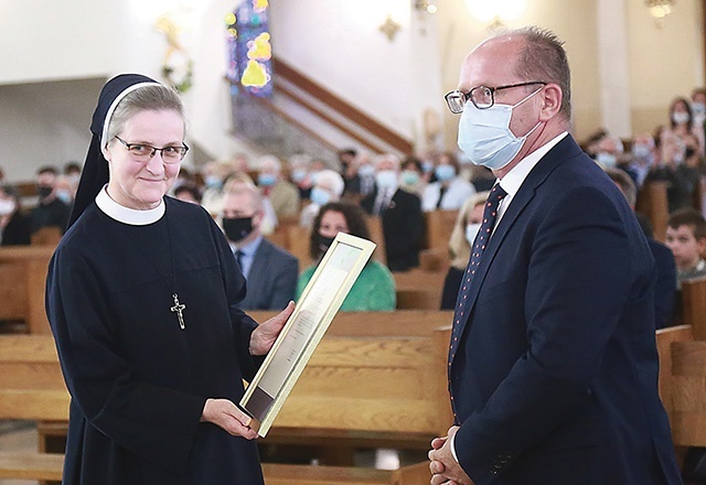 S. Maksymilla Pliszka odbiera od burmistrza Mariusza Szewczyka uchwałę Rady Miasta.