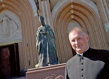 Ksiądz Marcin Rogala przy pomniku Prymasa Tysiąclecia, który stoi przed radomską katedrą.