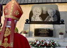 Biskup przed pomnikiem upamiętniającym ważne wizyty w historii sanktuarium.