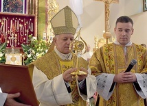 Arcybiskup ukazuje wiernym relikwiarz.