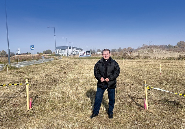 ▲	Proboszcz ks. Jacek Plech na placu budowy. Wbite w ziemię słupki znaczą obrys nowego budynku. Kapłan stoi w miejscu, w którym w przyszłości zlokalizowane będzie wejście główne.