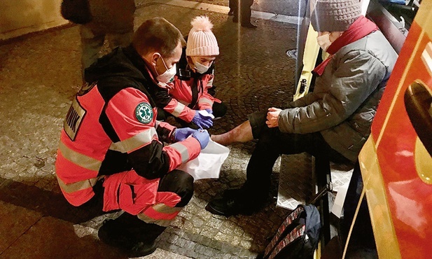 Osoby bezdomne z Białegostoku mogą liczyć na profesjonalną pomoc medyczną. Ks. Andrzej opatruje pacjentkę.