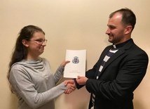 Kinga odbiera nagrodę od ks. Damiana Szewczyka, duszpasterza młodzieży.