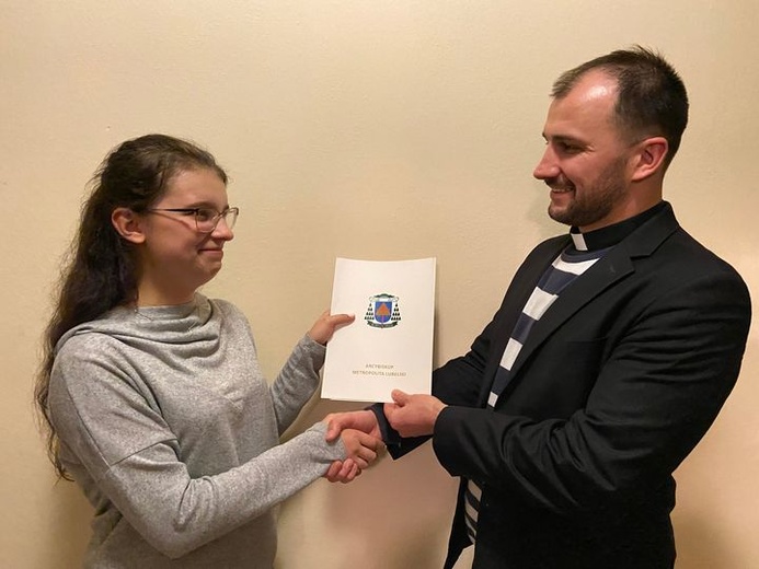 Kinga odbiera nagrodę od ks. Damiana Szewczyka, duszpasterza młodzieży.