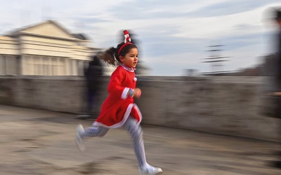 Dziewczynka w świątecznym stroju biegnie przez kamienny most w Skopje.
26.12.2021   Macedonia Północna