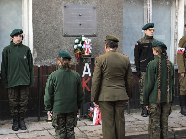 Złożenie kwiatów przed pamiątkową tablicą.