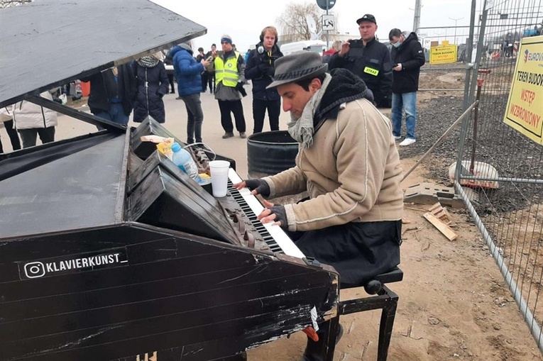 Sycylijski pianista gra na fortepianie na granicy w Medyce