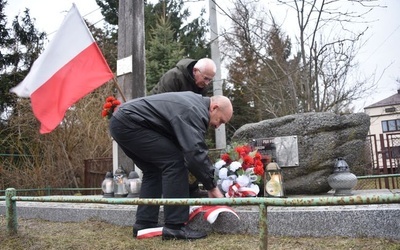 Składanie kwiatów przed pamiątkową tablicą.