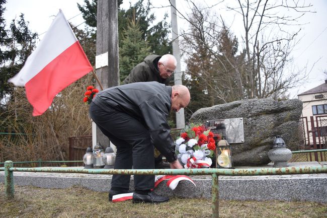 Składanie kwiatów przed pamiątkową tablicą.