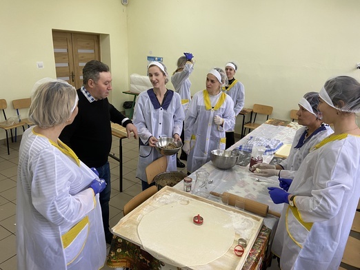 Dyrektor szkoły wraz z paniami z Ukrainy podczas lepienia pierogów.