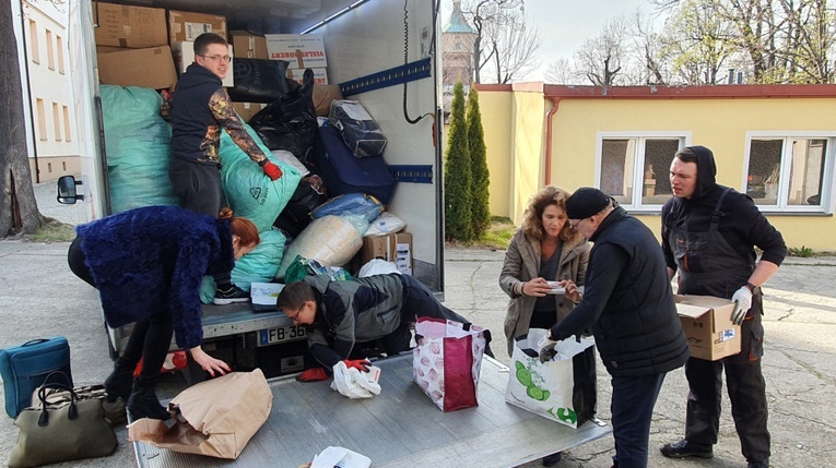 Klerycy i wolontariusze przy rozładunku transportu z Francji.