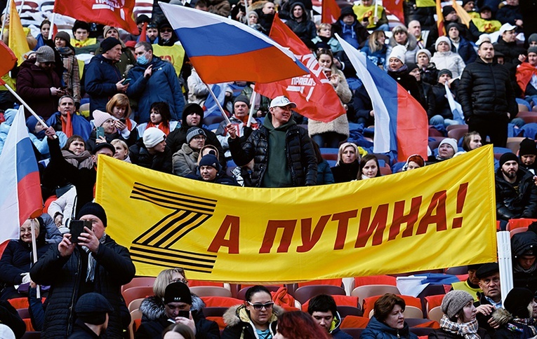 Demonstracja wsparcia dla wojny na Ukrainie.Stadion Łużniki, Moskwa, 18 marca 2022 r.  Na transparencie wykorzystany został znak „Z” – symbol agresji – rozwinięty w hasło: „Za Putina”. Literę „Z” tworzy tzw. wstążka św. Jerzego, symbolizująca zwycięstwo nad III Rzeszą.